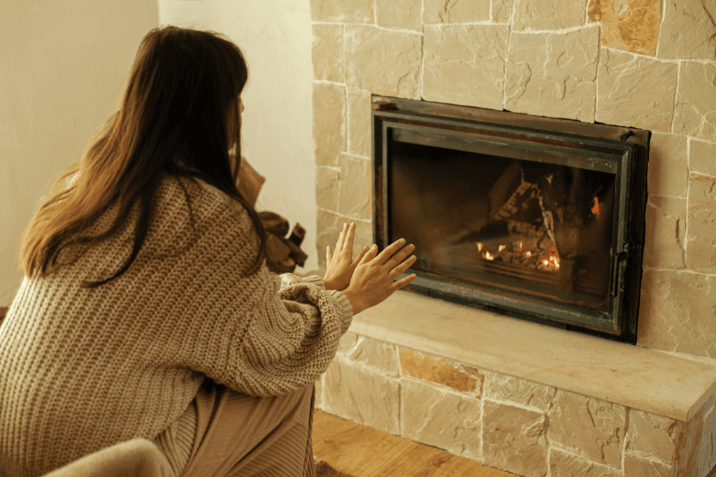 Woman being warmed by a gas fireplace serviced by Heaton Plumbing in Houston, Texas