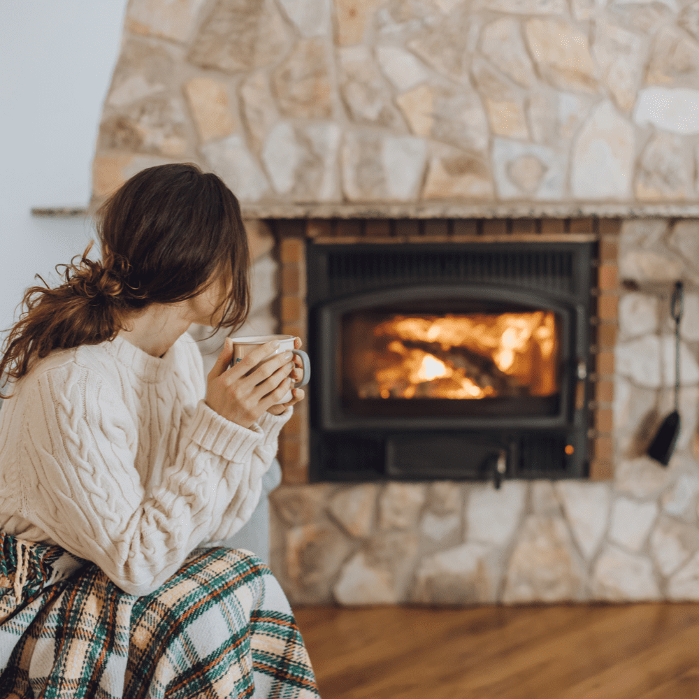 Beautiful woman being warmed by a gas fireplace with a hot cocoa serviced by Heaton Plumbing in Houston, Texas
